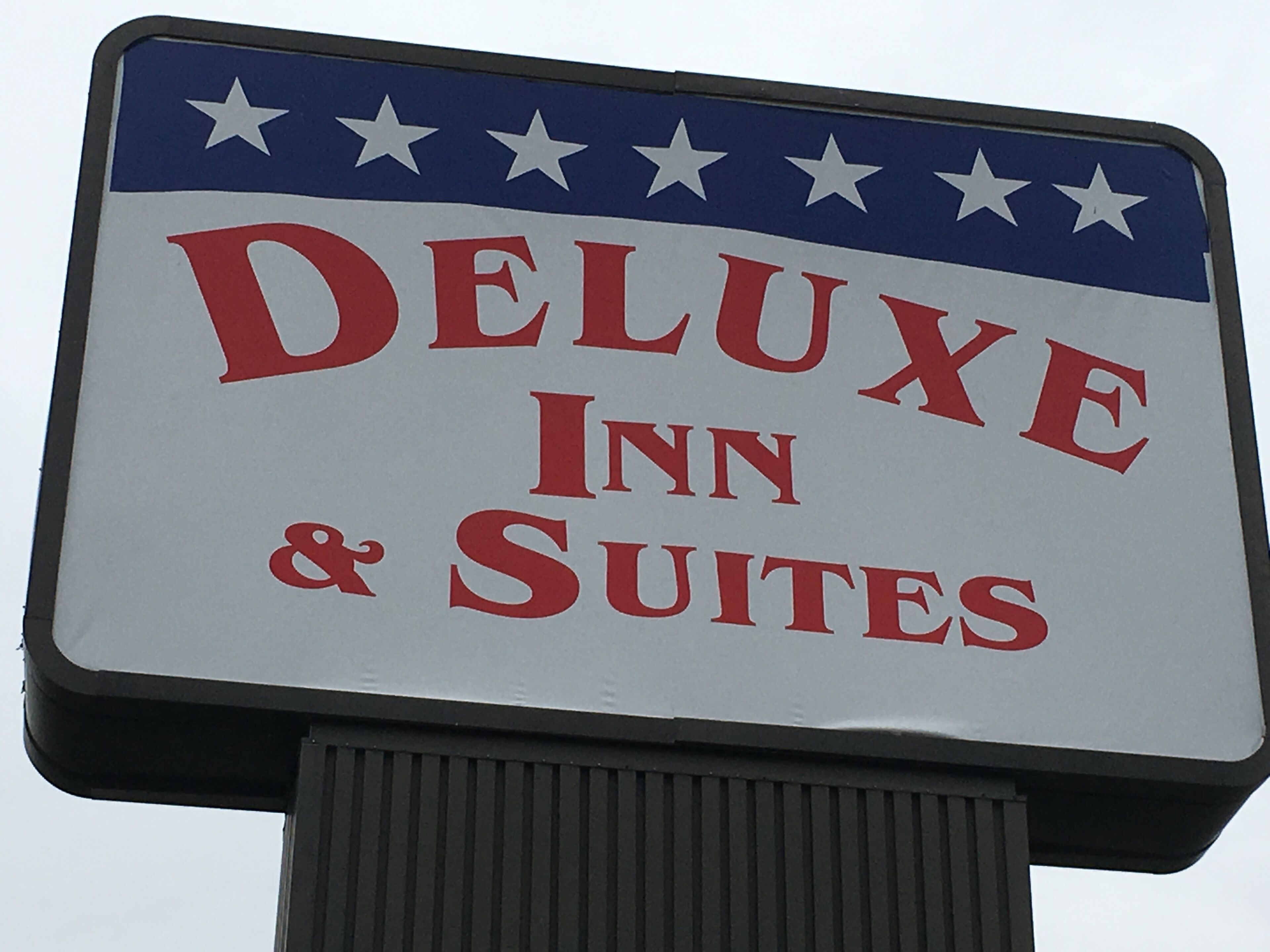 A sign for a hotel named "Deluxe Inn & Suites" with a patriotic design featuring stars and stripes.