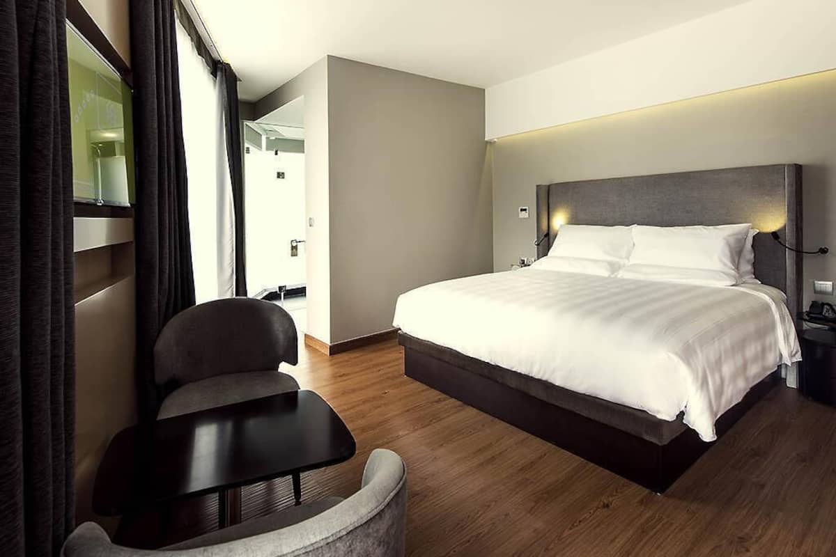 A hotel room with a large bed, a desk, and a chair.