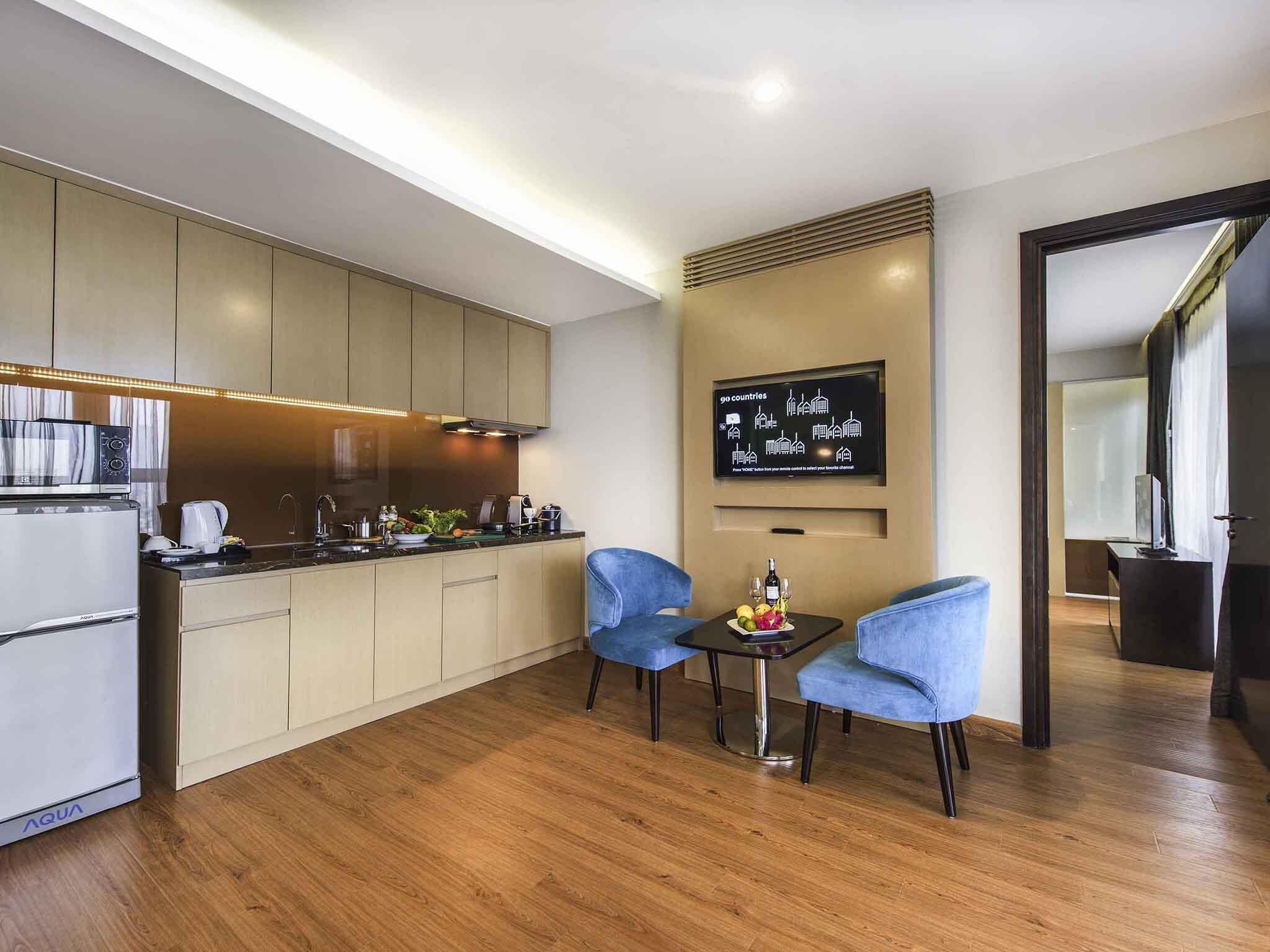 Eine moderne Küche mit Einbauofen, Mikrowelle und Kaffeemaschine, eine Essecke mit zwei Stühlen und einem an der Wand befestigten Flachbildfernseher.