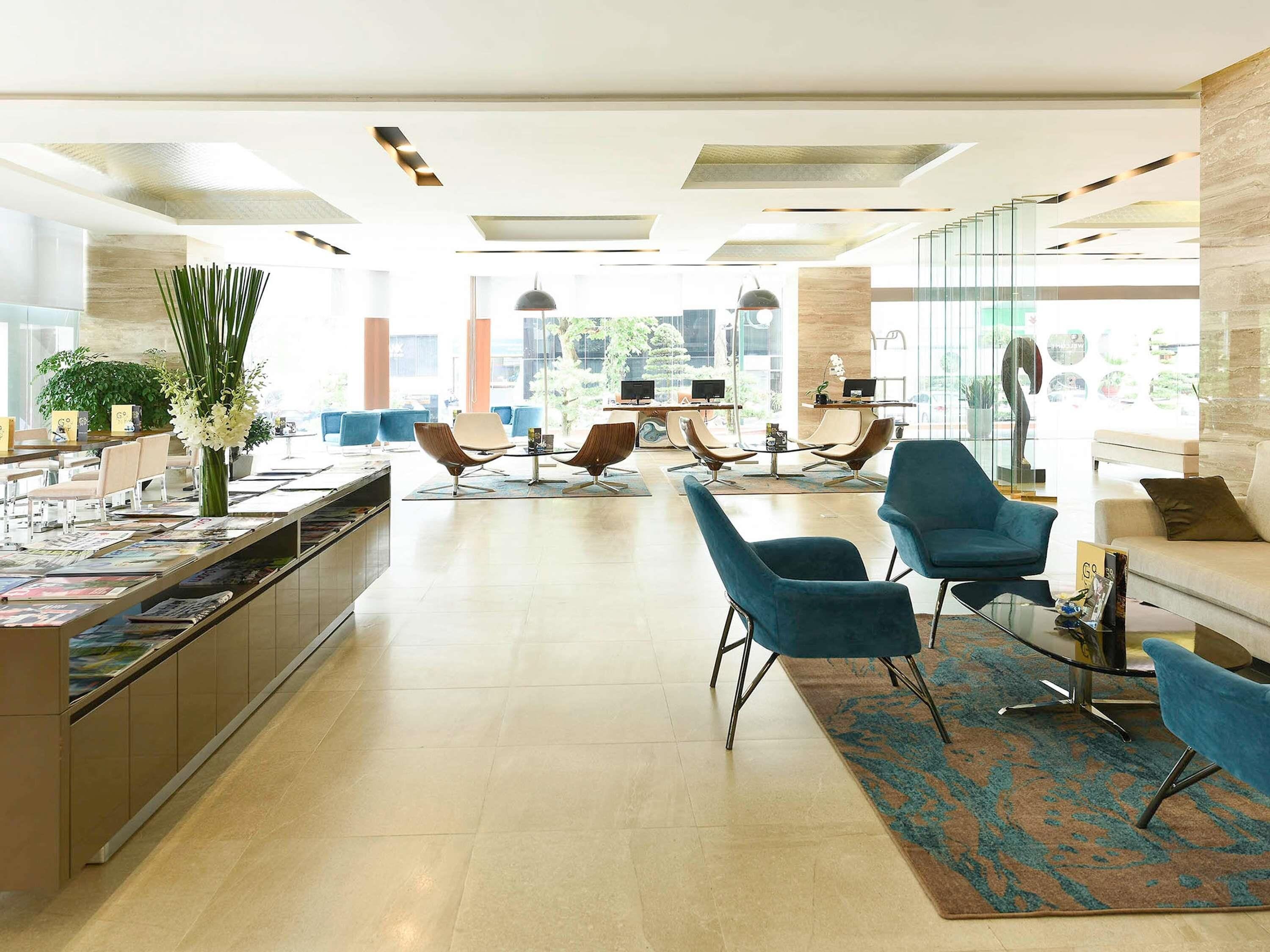 Un moderno vestíbulo de hotel con mostrador de recepción, zona de estar y grandes ventanales que ofrecen vistas al exterior.