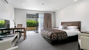Ein modernes Hotelzimmer mit Bett, Schreibtisch, Stuhl und Fernseher.