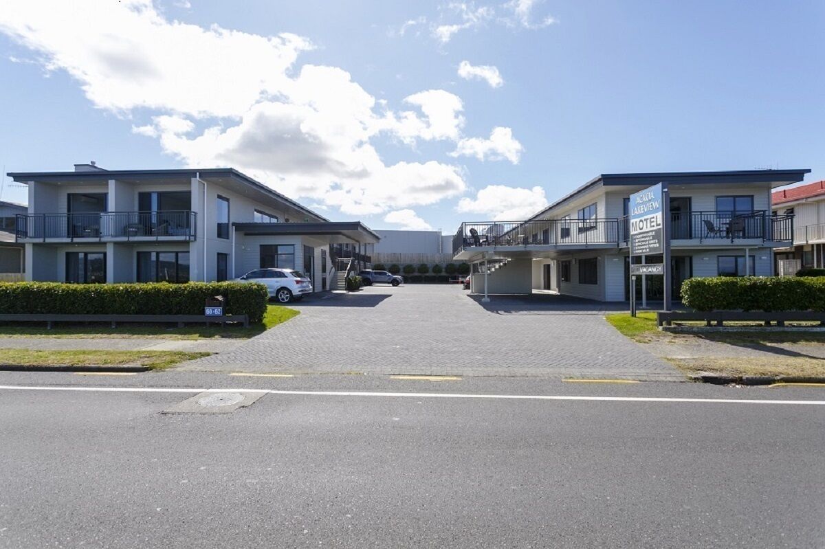 A motel with a two-story structure, a covered parking area, and a clear sky.