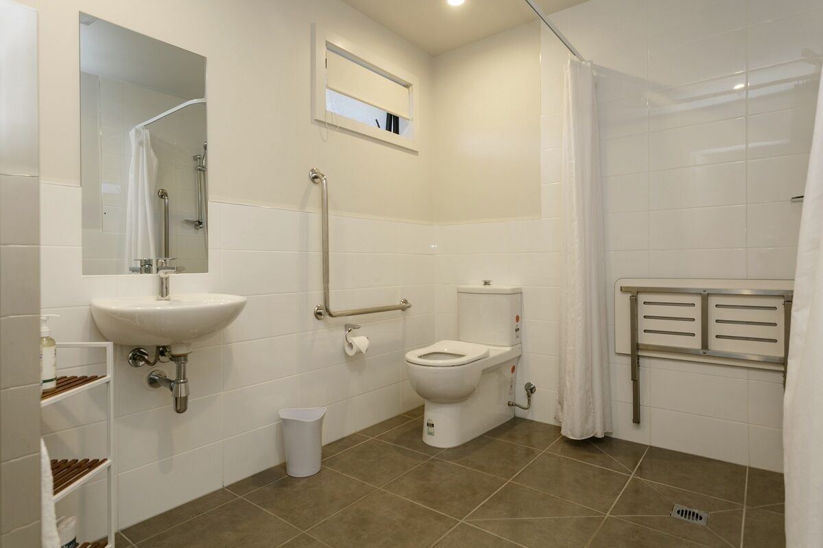 A modern bathroom with a white sink, toilet, and shower.