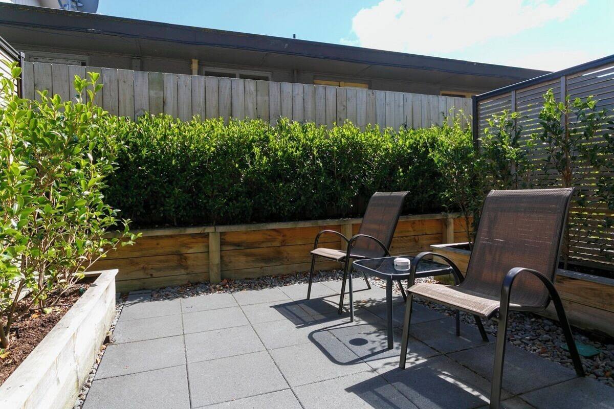 A patio with a wooden fence, a table, and two chairs.