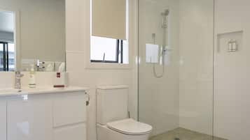 A modern bathroom with a toilet, sink, and glass-enclosed shower.