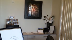 Ein Hotelzimmer mit Schreibtisch, einem gerahmten Auszeichnungsschein, einer Vase mit weißen Blumen und einem gerahmten Bild an der Wand.