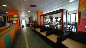Un hall d’hôtel comprenant un comptoir d’accueil, un espace salon et une vue sur la salle à manger.