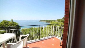 Un balcon avec vue sur la mer, une table et deux chaises.