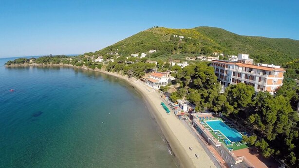 Un hôtel situé sur la côte, doté d’une piscine, d’un accès à la plage et offrant une vue sur les collines.