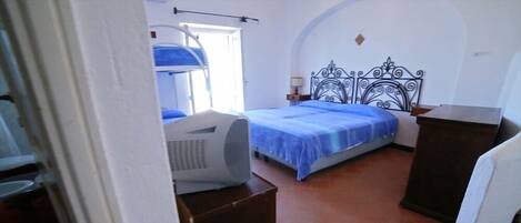 A bedroom with a bed, a heater, and a window.