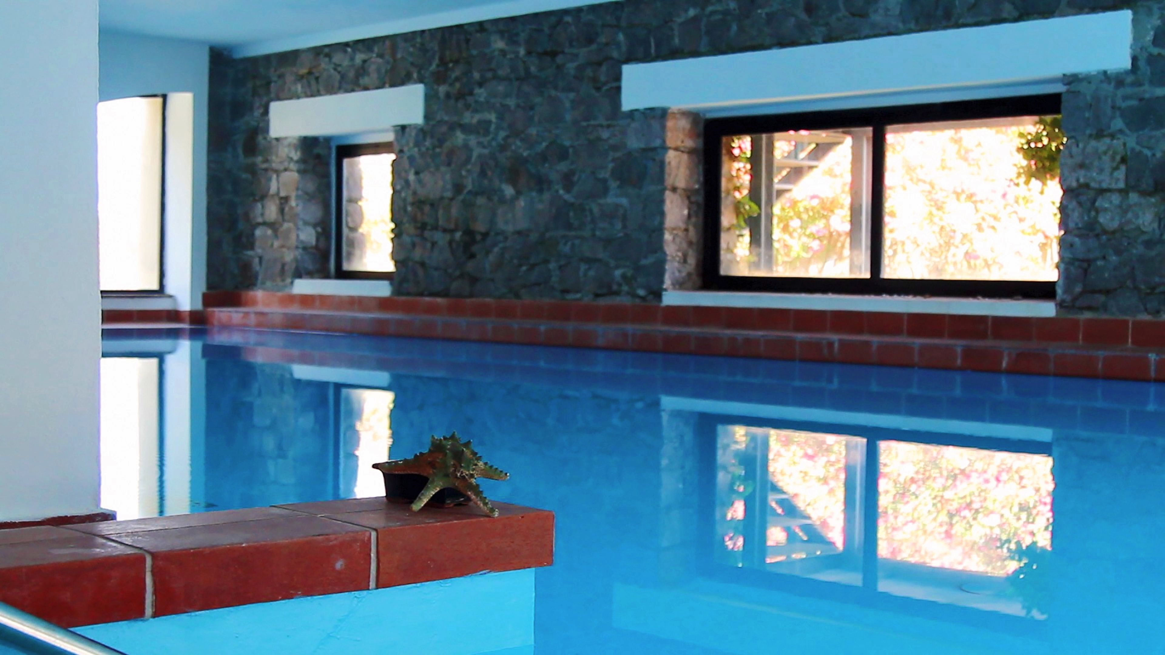 Une piscine avec des murs et des fenêtres en pierre.