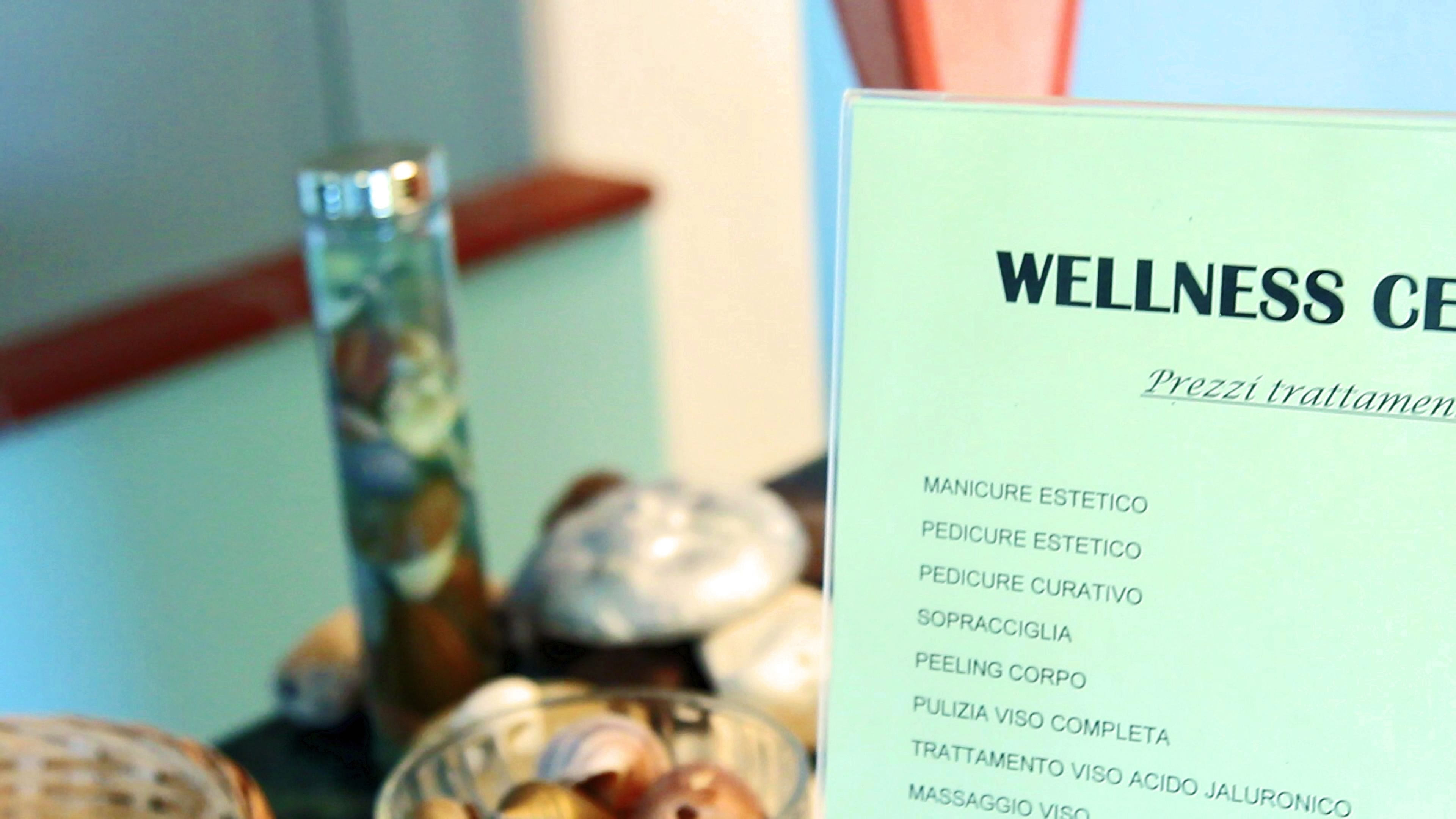 Segnaletica di un centro benessere che elenca trattamenti come manicure, pedicure e massaggi.