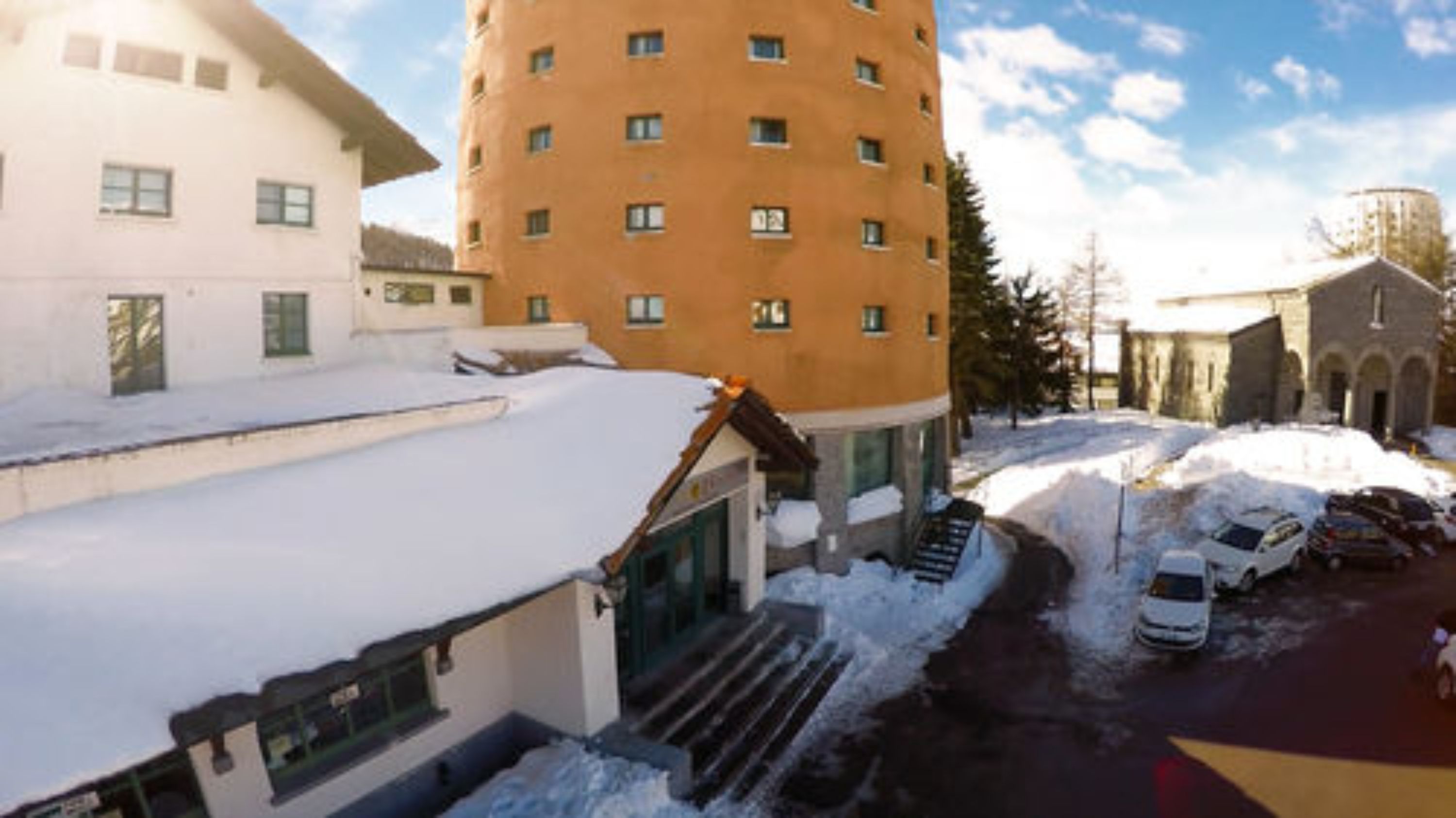 Un edificio de varios pisos con techo nevado y una escalera que lleva a la entrada.