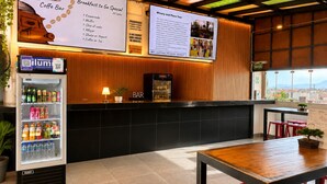 A cafe with a menu board, a refrigerator stocked with drinks, and a wooden counter. - Ica Adventures II - Hostel (Ica)