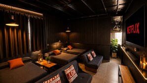 A cozy lounge area with multiple seating options, a Netflix sign, and a plant. - Ica Adventures II - Hostel (Ica)
