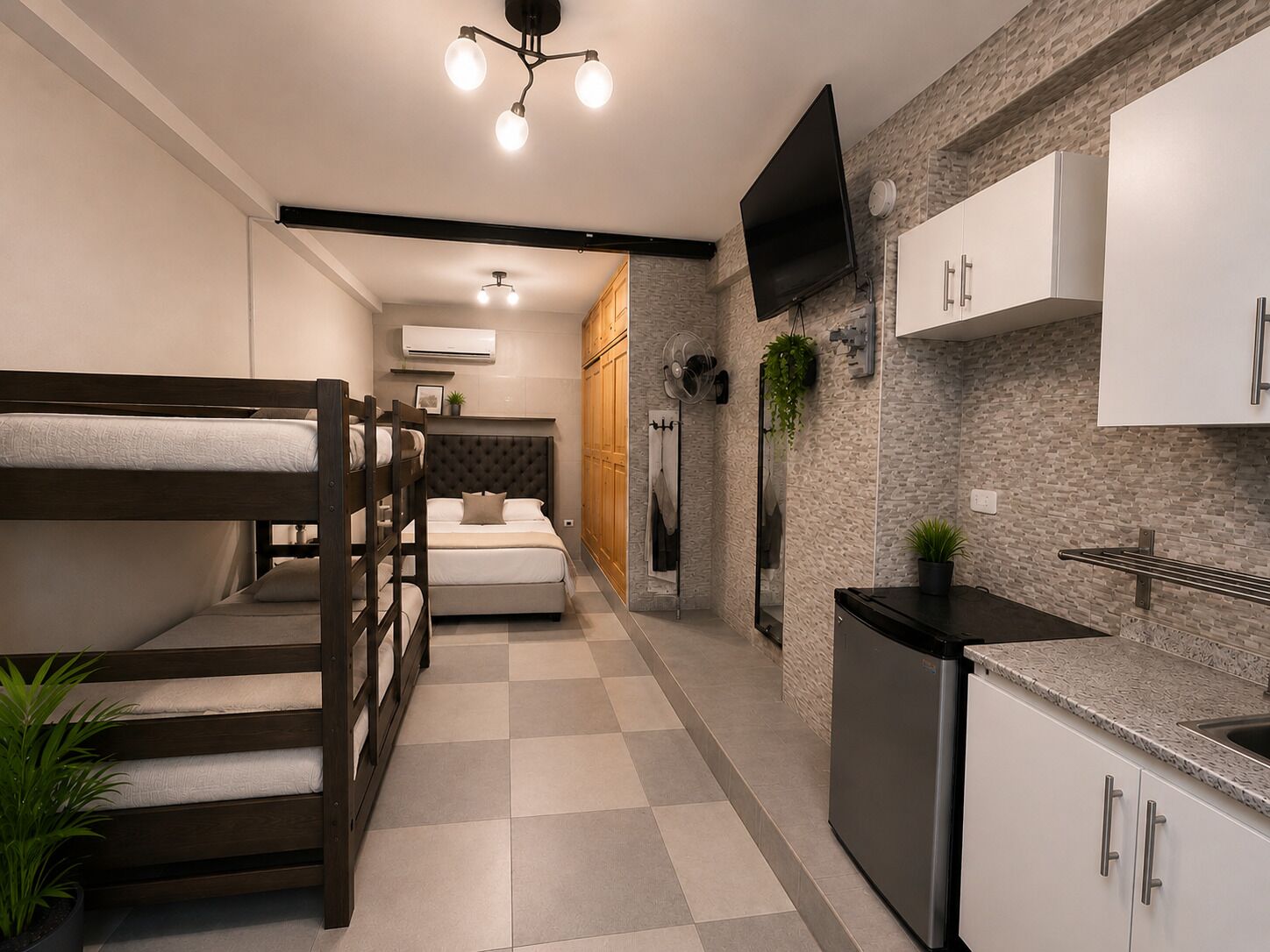 Habitación de hotel compacta con literas, kitchenette, televisor de pantalla plana y diseño moderno.