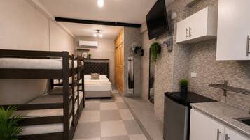 Habitación de hotel compacta con literas, kitchenette, televisor de pantalla plana y diseño moderno.