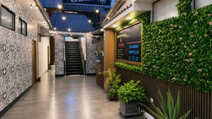 A hostel with a patterned wall, a staircase, a sign for laundry service, and potted plants. - Ica Adventures II - Hostel (Ica)
