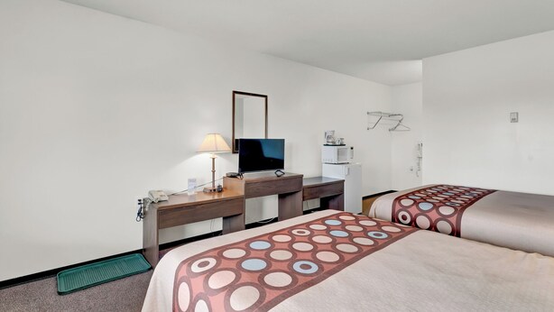 A hotel room with two beds, a desk, a mirror, a lamp, a phone, a microwave, and a small refrigerator. - Ranchmen Motel (Medicine Hat)