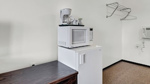 A compact kitchenette with a microwave and refrigerator, a coffee maker, and a drying rack on the wall. - Ranchmen Motel (Medicine Hat)