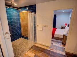 Un baño con azulejos azules, ducha con puerta de cristal y suelo de madera.