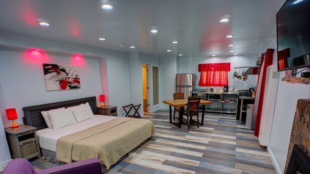 Una habitación de hotel con cama, escritorio, mesa de comedor con sillas, sofá y televisión.