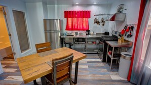 Una cocina compacta con una mesa de comedor, sillas, un refrigerador y una estufa.