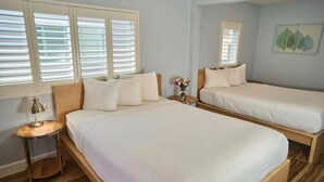 Een hotelkamer met twee bedden, een nachtkastje, een lamp en een spiegel aan de muur.