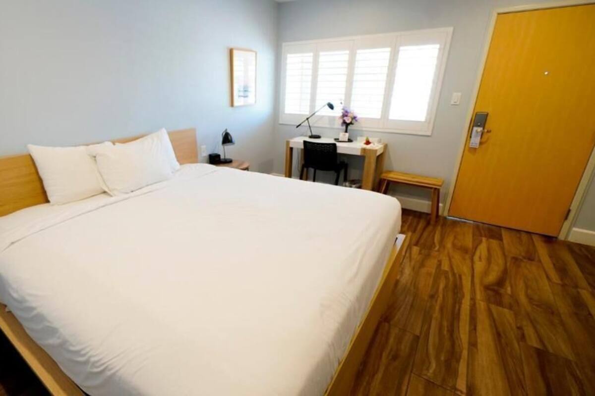 Un dormitorio con una cama grande, un escritorio, una silla, una mesita y una puerta.