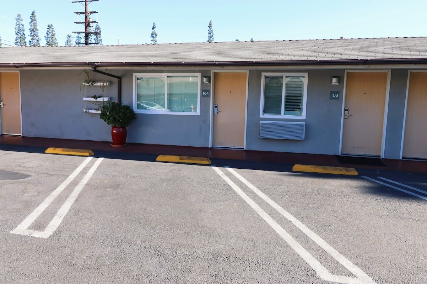A motel with numbered rooms, a parking lot, and a potted plant.