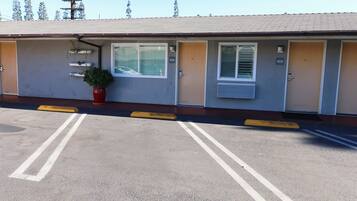 A motel with numbered rooms, a parking lot, and a potted plant.