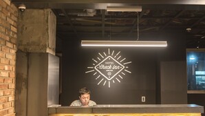 A hotel reception desk with a check-in counter, a clock with the hotel's name, and a modern ceiling design. - Check Inn Hotel Jeju (Jeju City)