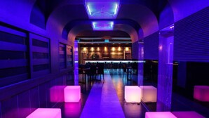 A modern bar area with a long counter, cushioned seating, and ambient lighting. - Check Inn Hotel Jeju (Jeju City)