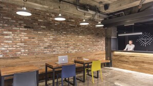A modern hotel lobby with exposed brick walls, wooden tables, and chairs. - Check Inn Hotel Jeju (Jeju City)
