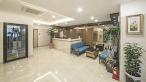 A modern lobby with a reception desk, seating area, and potted plants. - Harbor Hotel (Jeju City)