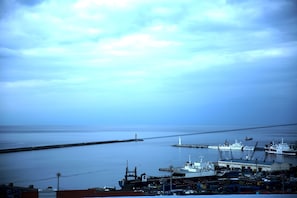 A harbor with ships docked, a lighthouse, and a calm sea. - Harbor Hotel (Jeju City)