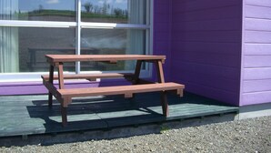 A wooden bench outside a building with purple walls and large windows. - Cottage Ken&Mary (Biei)