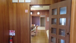 A wooden interior hallway with a fire extinguisher, a clock, and a door with frosted glass panels. - Cottage Ken&Mary (Biei)