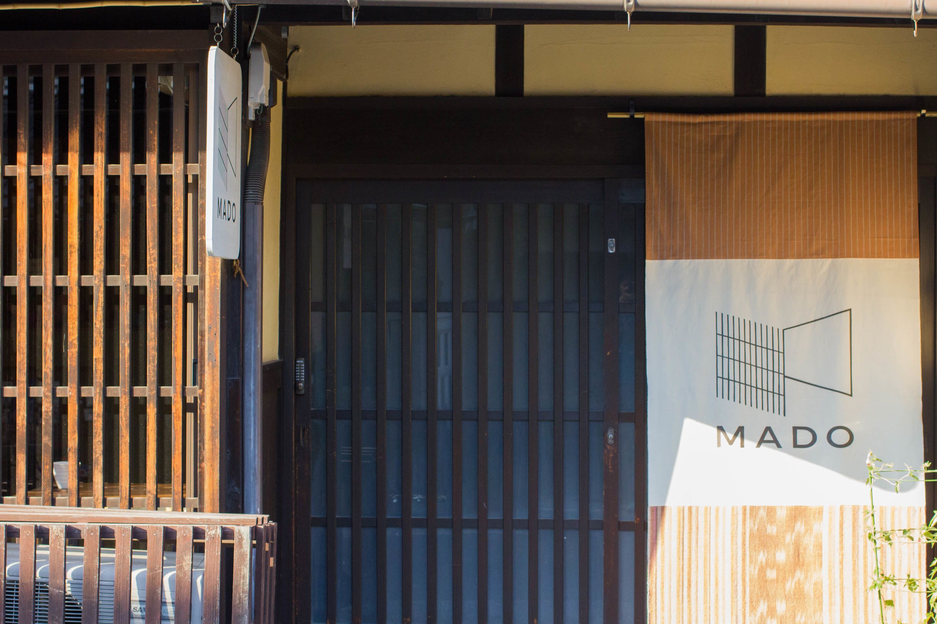 A building entrance with a large wooden gate and a sign that reads "MADO".