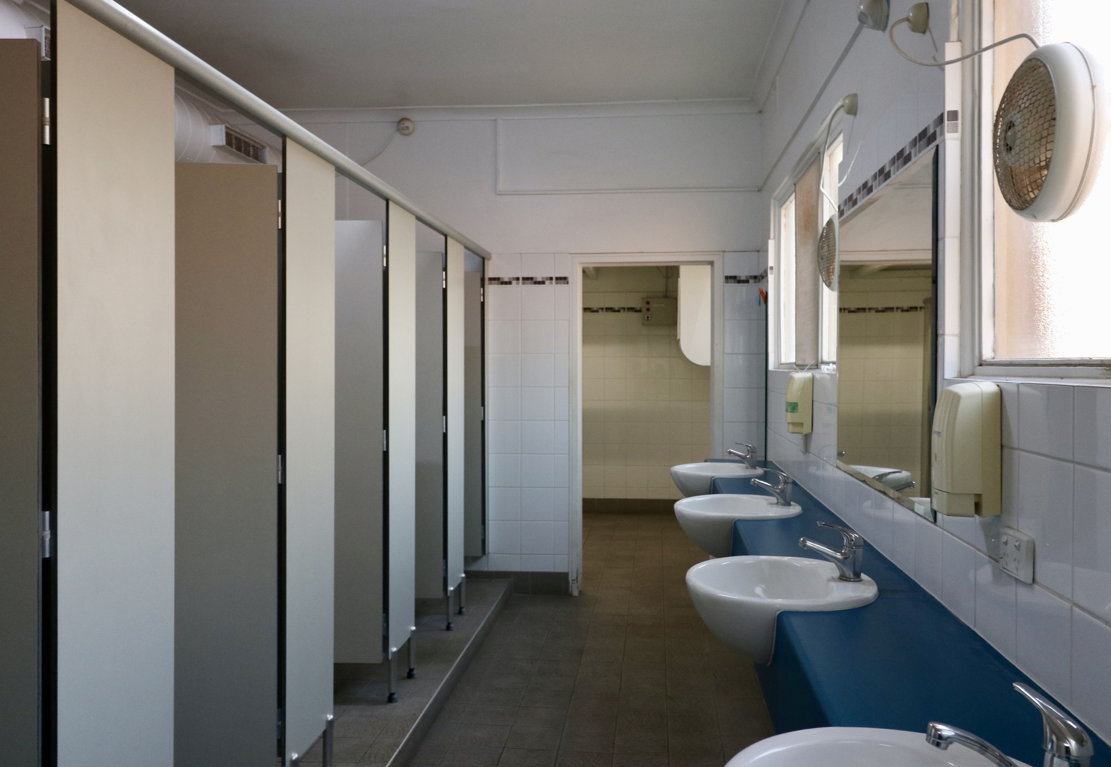 A row of sinks with mirrors and soap dispensers in a public restroom.