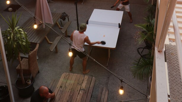 A courtyard with a dining area, tables, chairs, and string lights. - Britannia on William - Hostel (Perth)