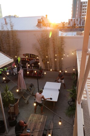 A courtyard with a dining area, tables, chairs, and string lights. - Britannia on William - Hostel (Perth)