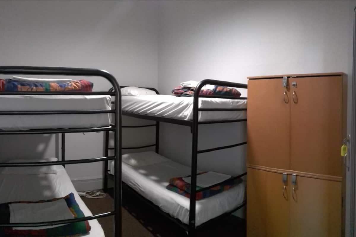 Ein Schlafsaalzimmer mit Etagenbetten und einem Holzschrank.