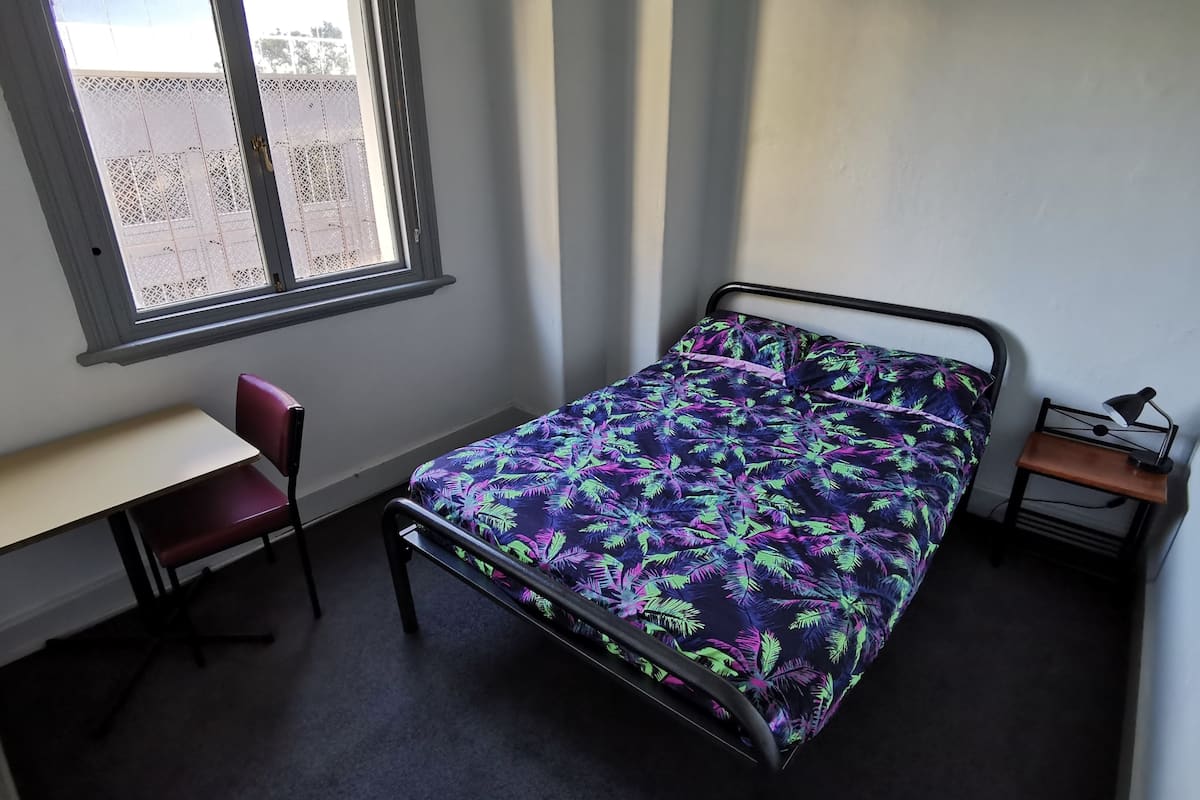 Ein Schlafzimmer mit Bett, Schreibtisch, Stuhl und Nachttisch.