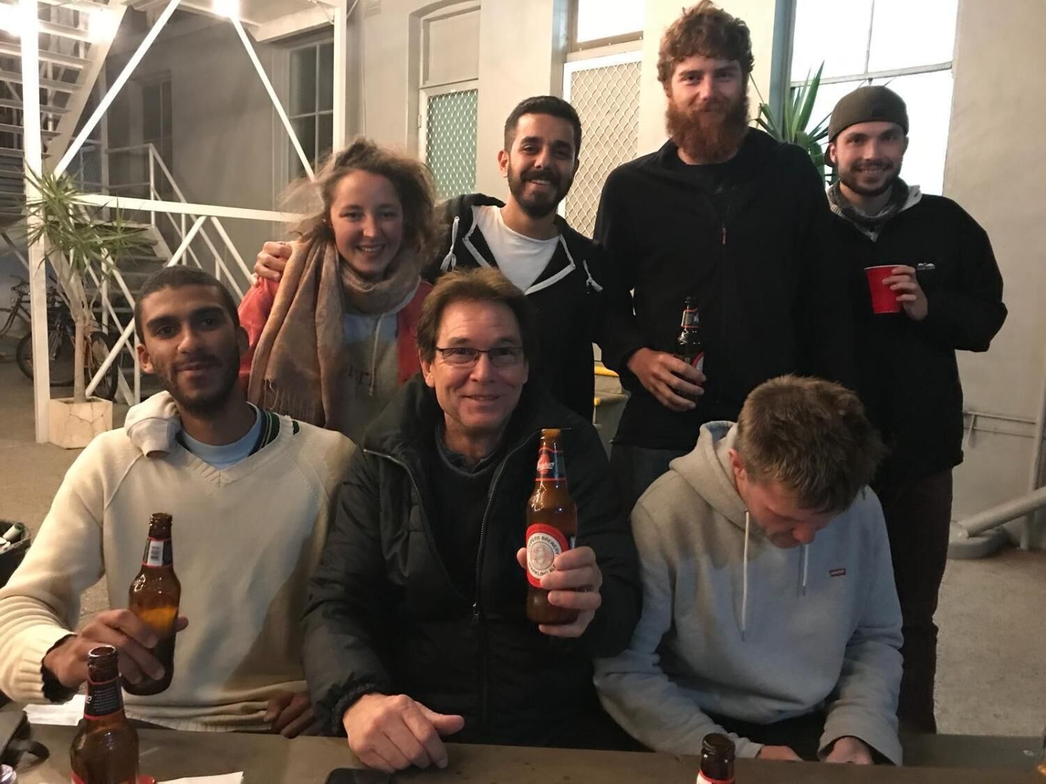 Een groep mensen in een kamer met een trap en een plant.