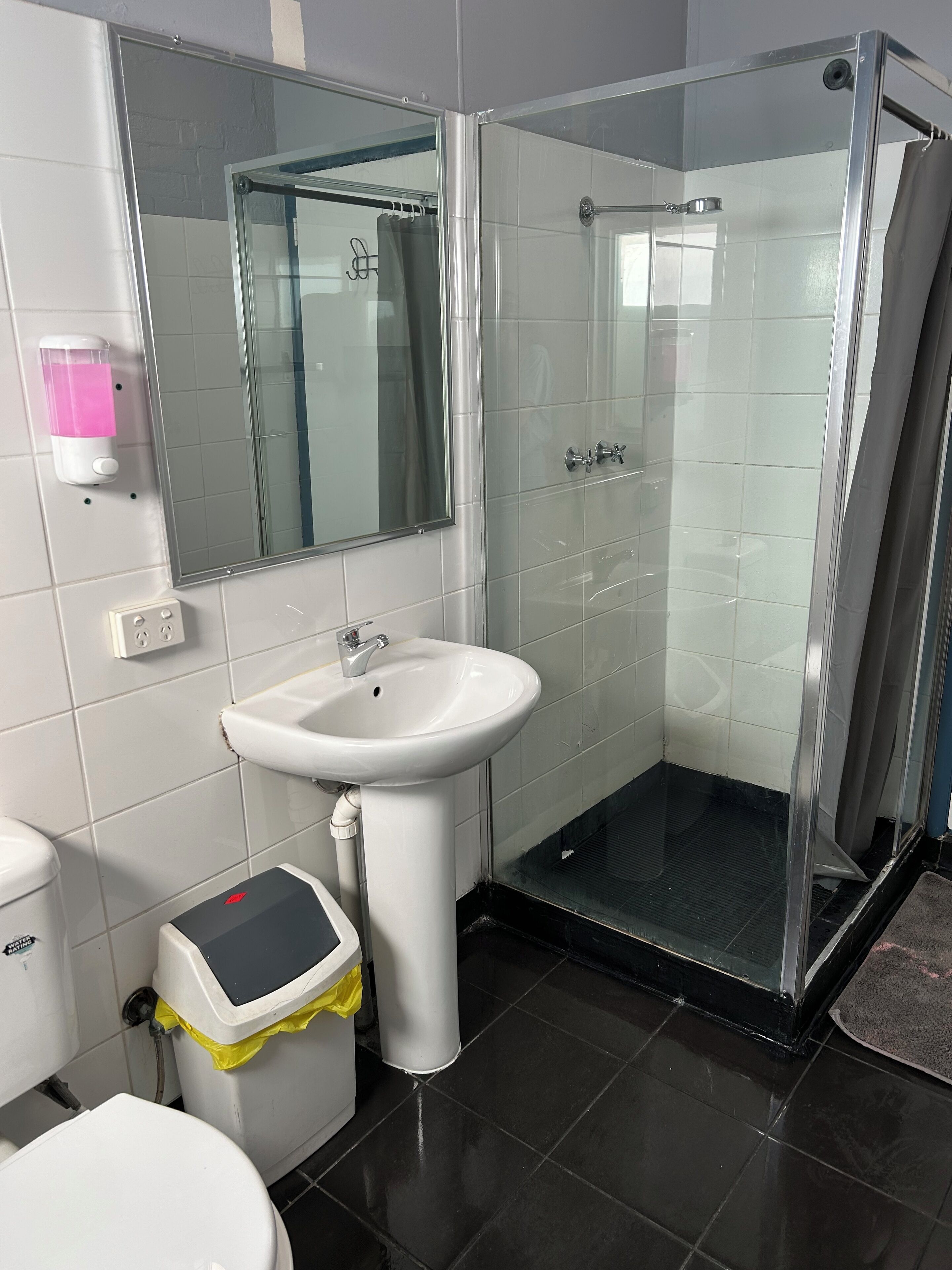 Un baño con cabina de ducha de vidrio, lavabo blanco y retrete.