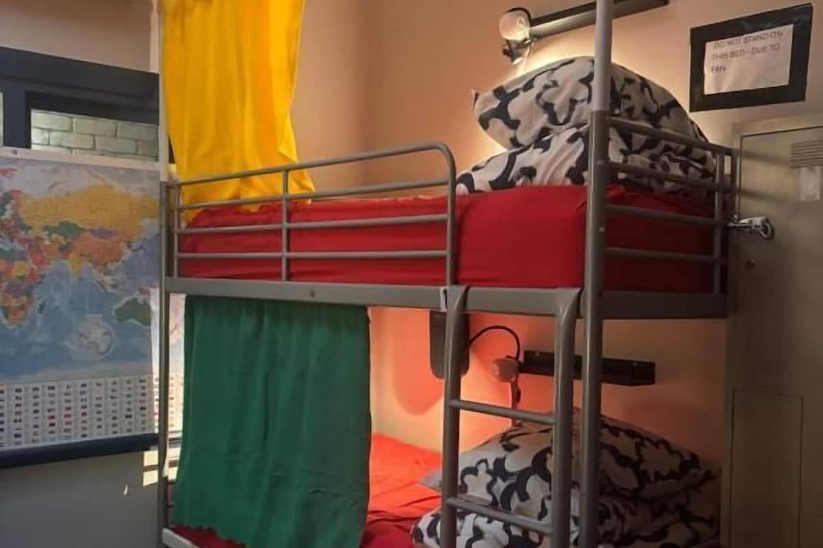 A bunk bed room with a world map, a small desk, and a window with a view of the outside.