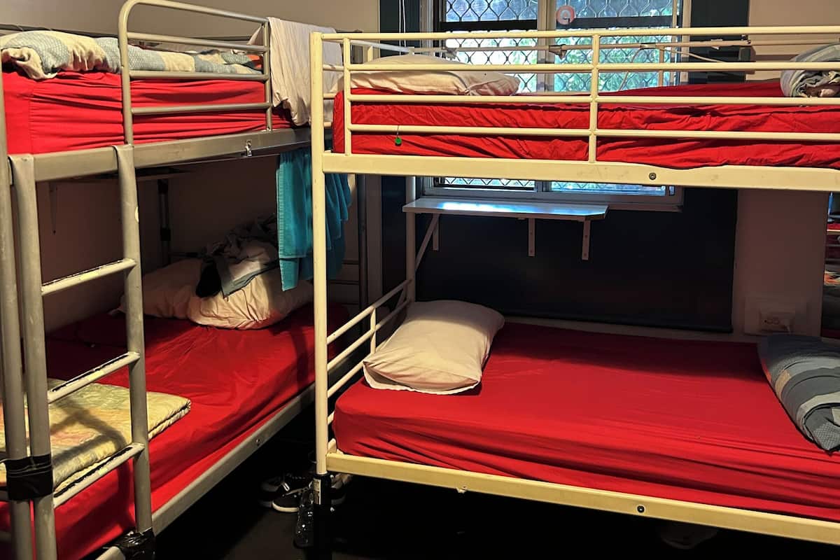 A bunk bed room with a window, a heater, and a pair of sandals on the floor.