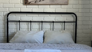 A bed with a white patterned bedspread, two pillows, and a folded white towel.