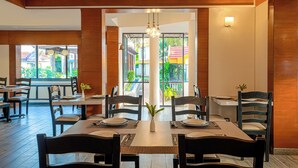 A restaurant with wooden beams, large windows, and a central dining table set for four.